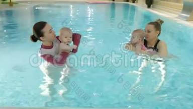 游泳课。 在游泳池里教婴儿游泳的母亲